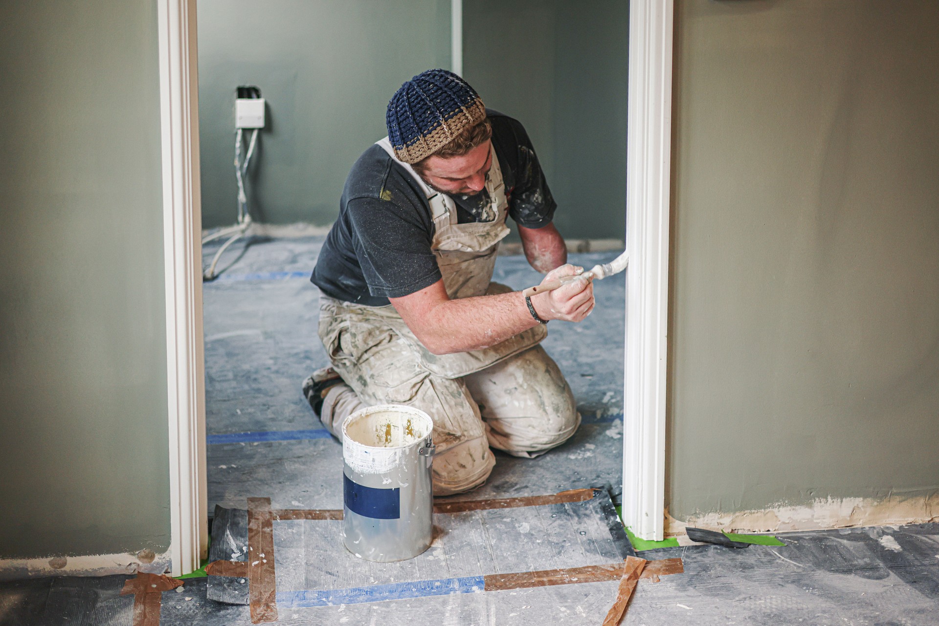 Young, skilled Painter & Decorator overcoming the disability of having one hand as he carefully and skilfully paints a door architrave in a residential house