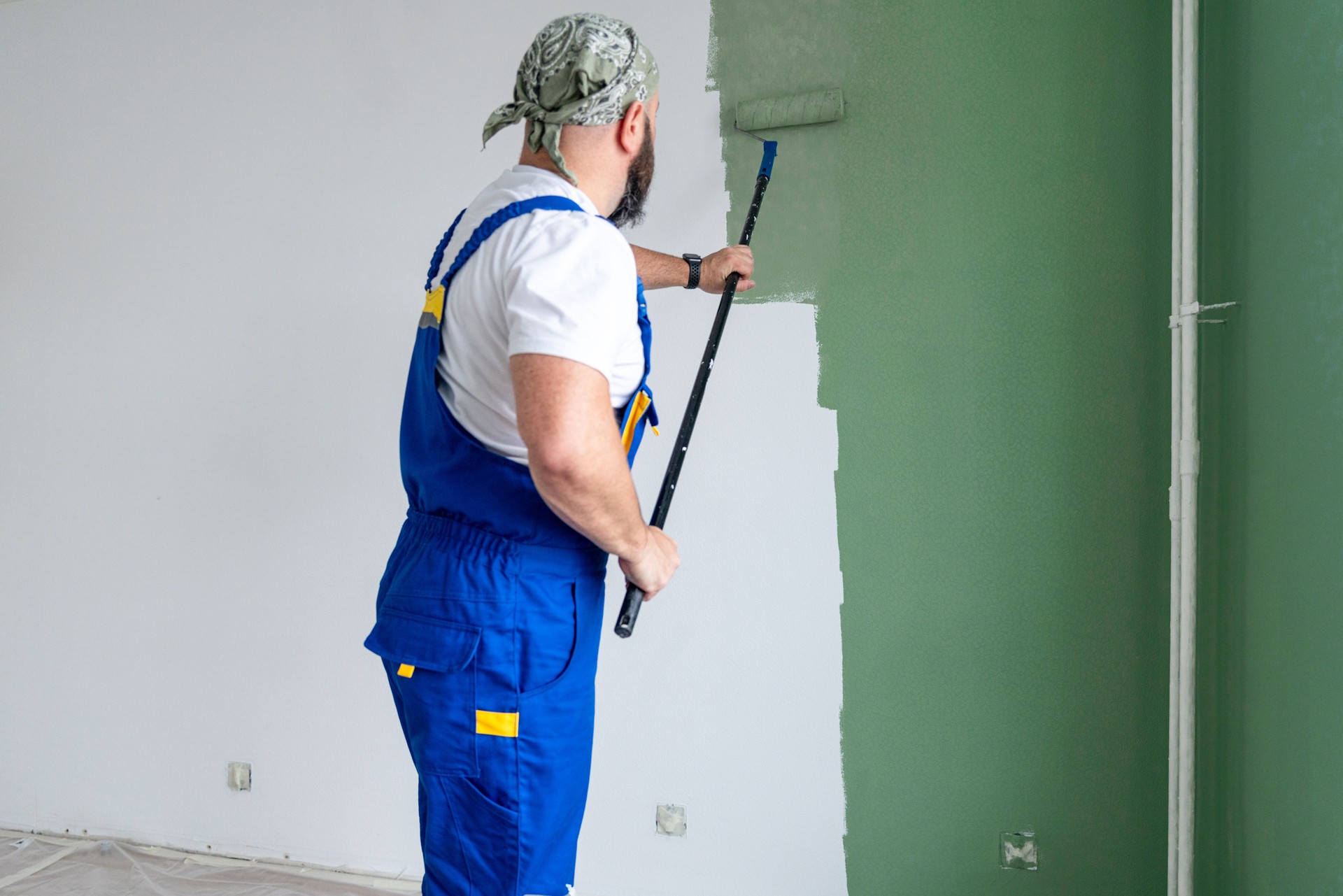 House renewal concept. A man painting wall with green paint.